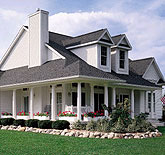 White vinyl-sided home with a wraparound porch and dormers